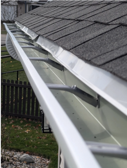 Gouttière blanche en aluminium — intérieur propre, suspensions visibles, bardeaux gris et arrière-plan résidentiel